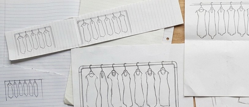 Lineup, working drawings: rough pencil sketches on lined and plain paper, overlapping on a table, each showing a rail with seven identical empty slumped skins hanging from hangers.